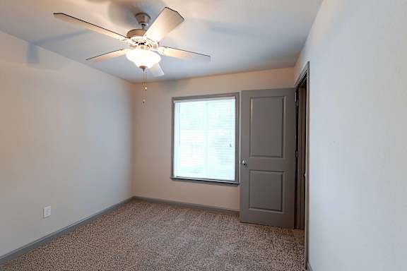 A room with a ceiling fan and a window.