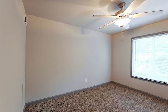 A room with a ceiling fan and a window.
