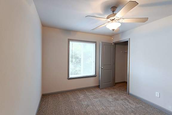 A room with a ceiling fan and a window.