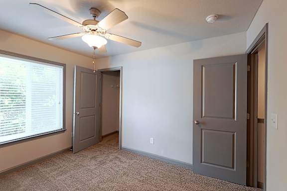 A room with a ceiling fan and two doors.
