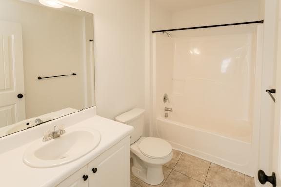 A white bathroom with a toilet, sink, and bathtub.