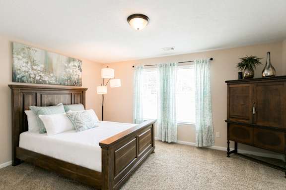 A bedroom with a large bed and a wooden dresser.