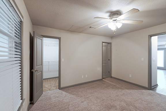 A room with a ceiling fan and carpeted floor.