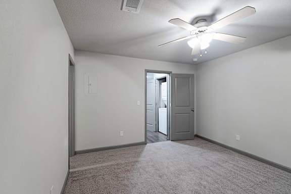 A room with a ceiling fan and carpeted floor.