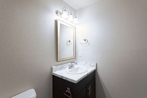 A bathroom with a sink, mirror, and toilet.