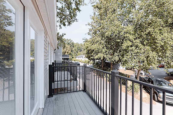 A balcony with a black railing and a view of a street with cars.