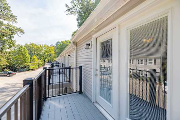 A white house with a black gate and a wooden deck.