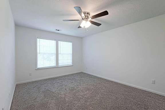 an empty living room with a ceiling fan and a window at Sterlington Apartments, Grovetown, GA