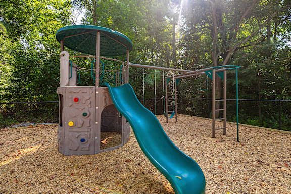A playground with a green slide and a grey structure at Helena Springs, Georgia