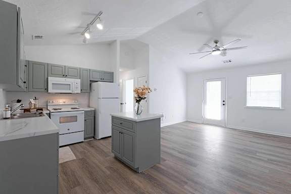 an open kitchen and living room with white appliances at Sterlington Apartments, Grovetown, GA