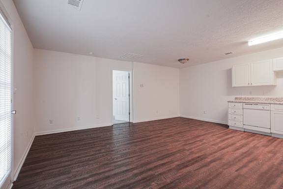 A room with wooden flooring and white walls.
