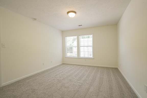 A room with a carpeted floor and a window.