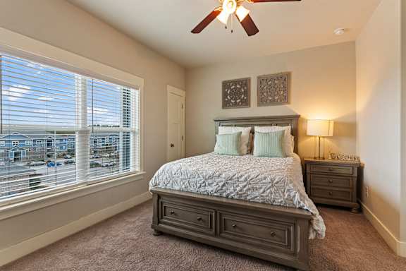 A bedroom with a large bed and a ceiling fan.