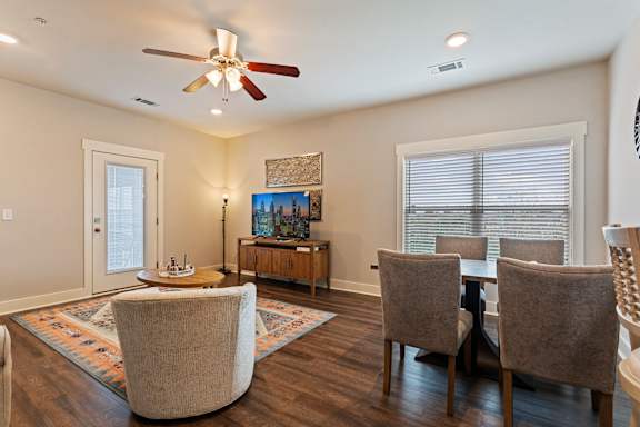 A living room with a ceiling fan and a rug.