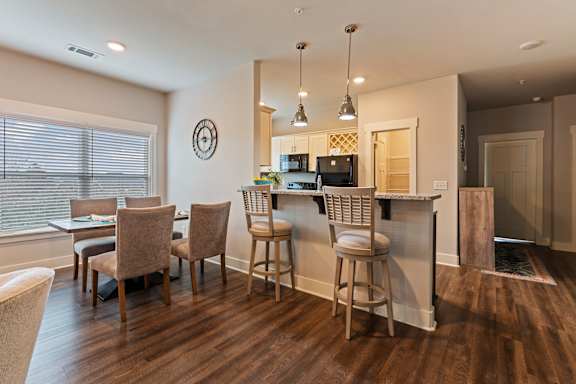 A kitchen with a bar and chairs.