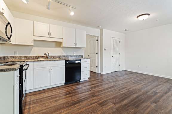 A kitchen with white cabinets and a black oven.