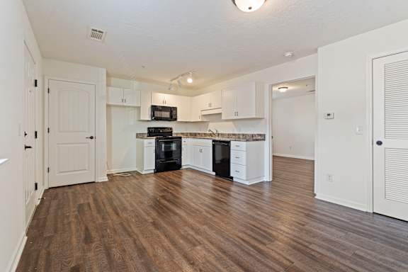 A kitchen with white cabinets and a black dishwasher.