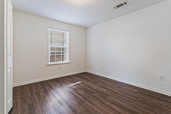 A room with a window and wooden flooring.