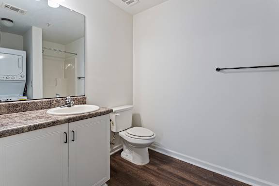 A white bathroom with a toilet, sink, and mirror.