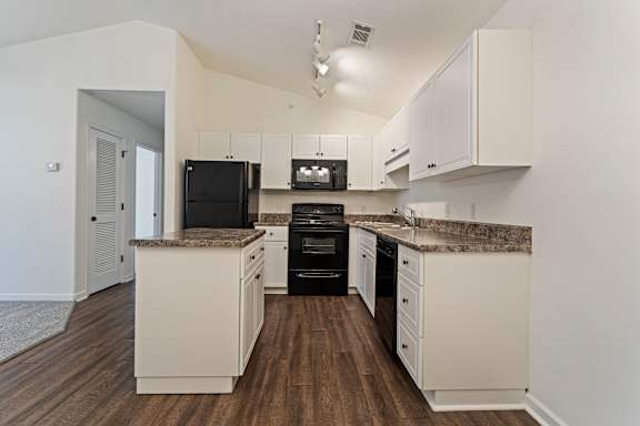 A kitchen with white cabinets and a granite countertop.