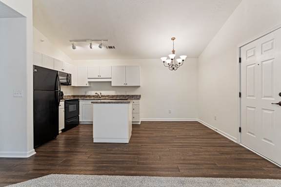 A kitchen with black appliances and white cabinets.