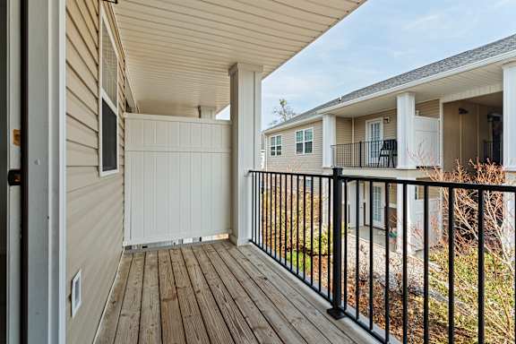 A balcony with a black railing and a wooden floor.
