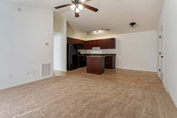 A room with a ceiling fan and a kitchenette.