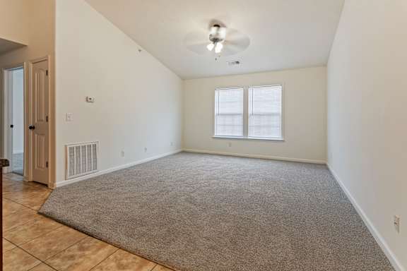 A room with a ceiling fan and a rug on the floor.