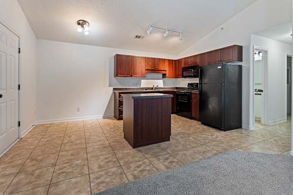 A kitchen with black appliances and brown cabinets.