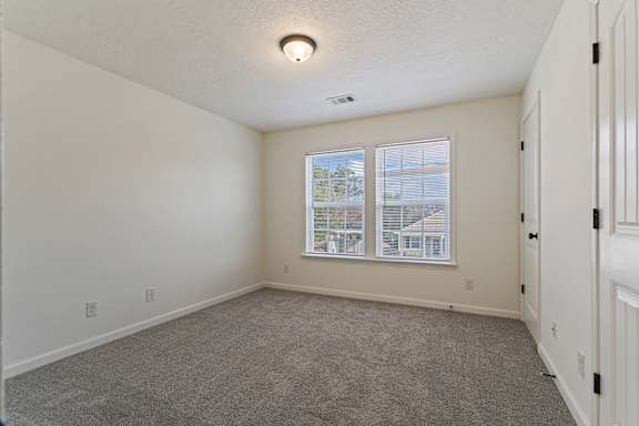 A room with a window and a carpeted floor.
