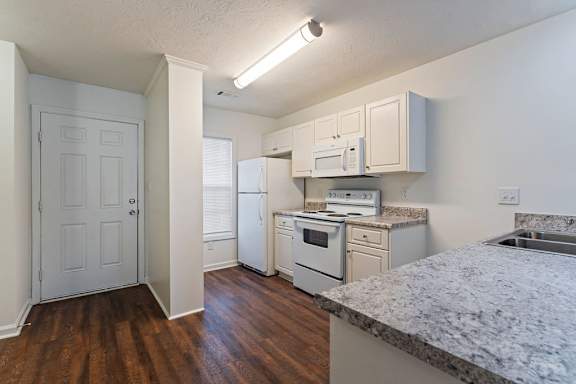 A kitchen with white appliances and wooden floors.