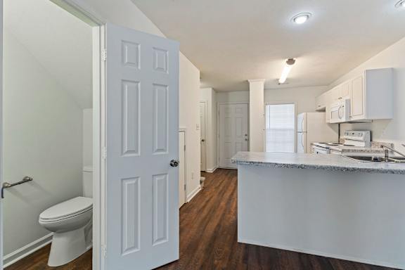 A white door is open to a kitchen area.