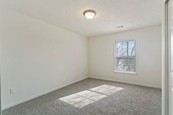 A room with a window and a carpeted floor.