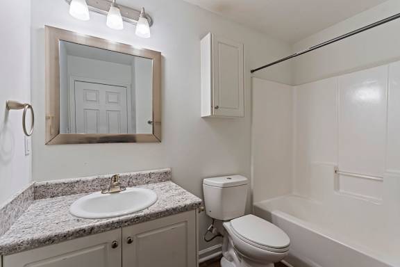 A bathroom with a toilet, sink, and mirror.