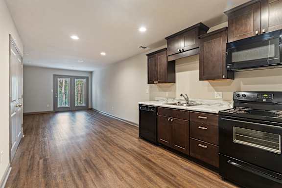 A kitchen with dark wood cabinets and black appliances.
