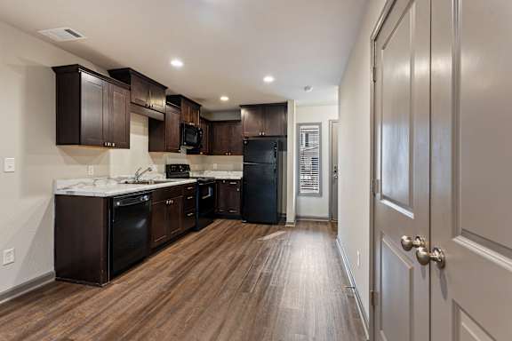 A kitchen with dark wood cabinets and a black refrigerator.