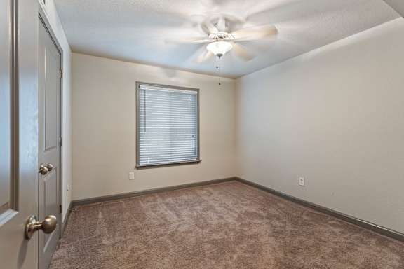 A room with a ceiling fan and a window with blinds.