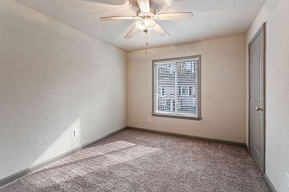 A room with a ceiling fan and a window with blinds.