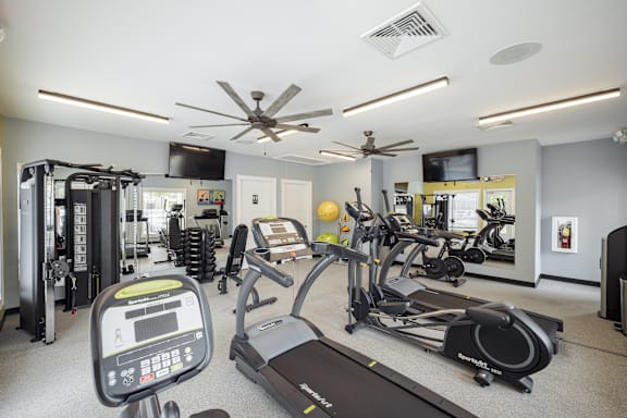 A gym with treadmills, elliptical machines, and other exercise equipment.