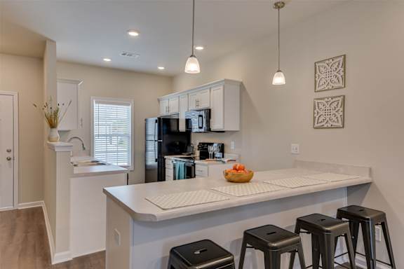 a kitchen with a counter top and stools at The Vista Apartments &amp; Townhomes, Warrenville
