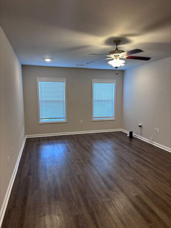 A room with a ceiling fan and two windows.
