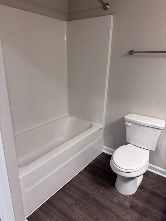 A white toilet in a small bathroom with a white bathtub.
