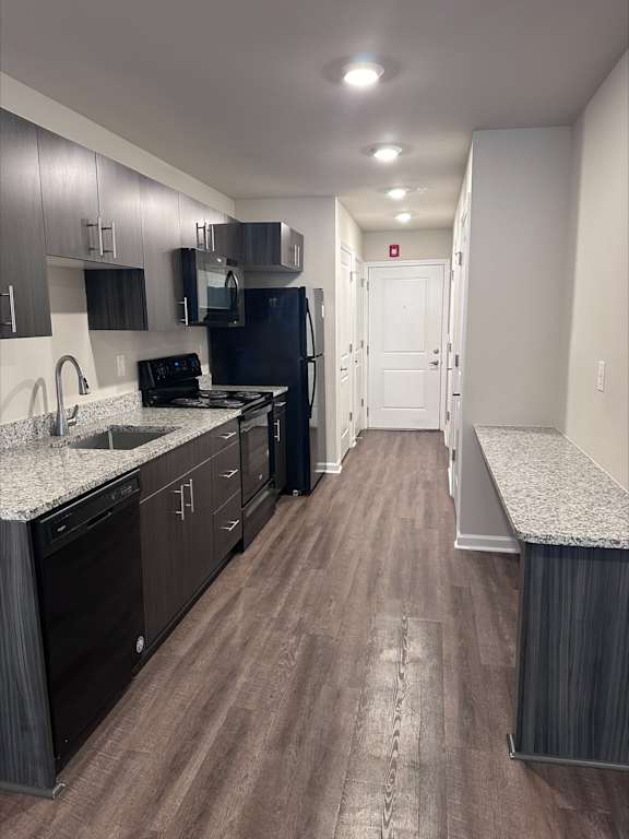 A kitchen with dark wood cabinets and a black fridge.