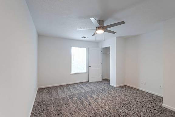 Carpeted bedroom with ceiling fan and closet at Sterlington Apartments, Grovetown, GA