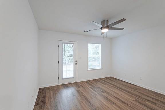 Living area with ceiling fan, hardwood-style flooring, and door to back patio area at Sterlington Apartments, Grovetown, Georgia