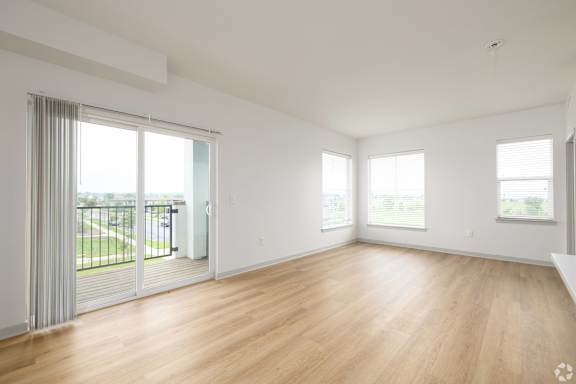 A spacious room with wooden floors and sliding glass doors. at Arbour Commons, Westminster, CO