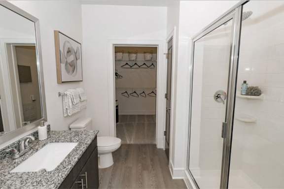 A bathroom with a walk in shower and a toilet at Cue Luxury Apartments, Cypress, Texas