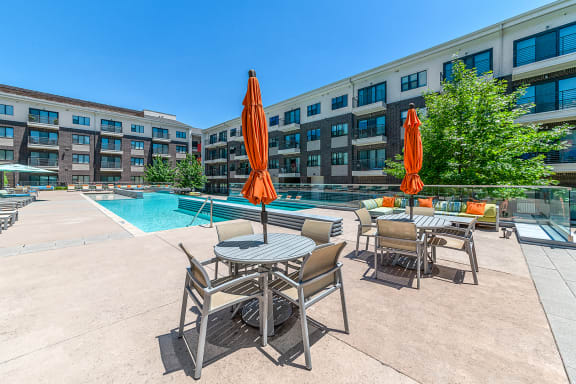 our apartments have a large pool and patio with tables and chairs