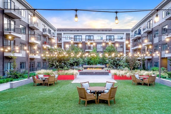 an open courtyard with tables and chairs in front of an apartment building