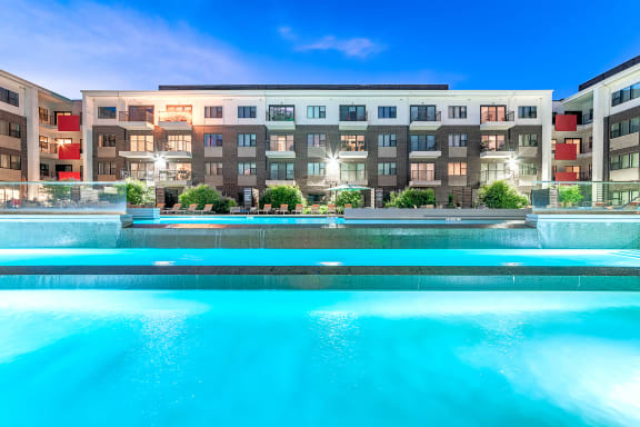 a large swimming pool in front of a hotel with a blue sky